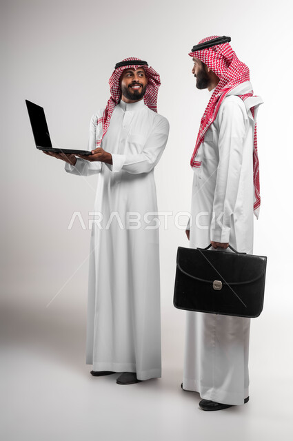 تطوير العمل وحل المشكلات لتحقيق أهداف الشركة، دمج العمل مع التقنية والتكنولوجيا، بورتريه لمدير عربي سعودي خليجي يرتدي الشماغ والثوب التقليدي يحمل بيده حقيبة جلد سوداء يقوم بمتابعة إنجاز الموظف، العمل الجماعي وروح الفريق الواحد، صورة الجسم بالطول الكامل، خلفية بيضاء