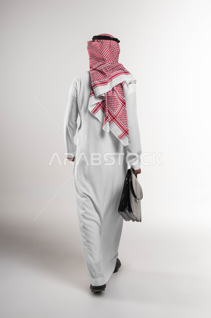 Paying attention to elegance and external appearance, going to work actively, a portrait from the back of a Saudi Arabian Gulf businessman wearing a shemagh and traditional dress, carrying a handbag, going to work, full body portrait, white background