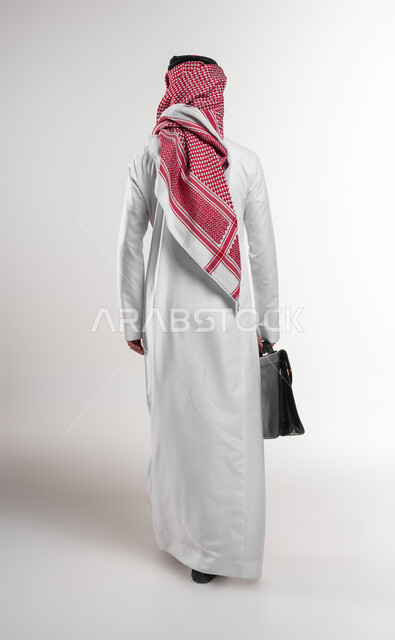 Paying attention to elegance and external appearance, going to work actively, a portrait from the back of a Saudi Arabian Gulf businessman wearing a shemagh and traditional dress, carrying a handbag, going to work, full body portrait, white background