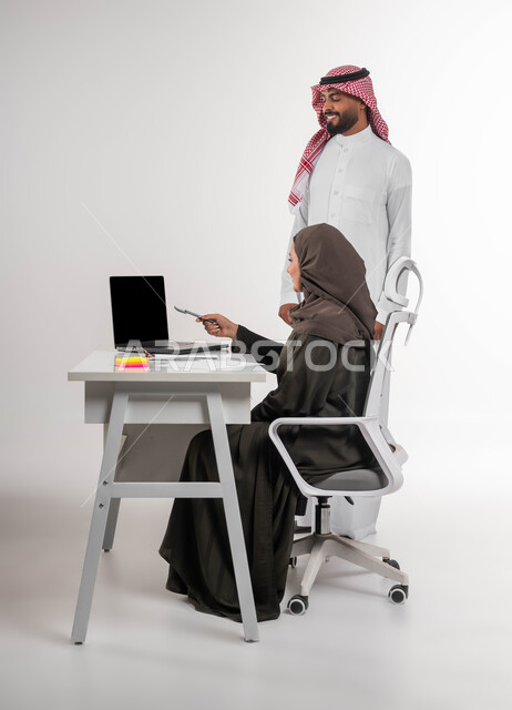 إدارة الأعمال باستخدام التقنيات الحديثة، الاشارة الى الحاسوب المحمول للانتباه للملاحظات وتطبيقها، مفهوم التعاون والعمل الجماعي، متابعة إنجازات مهام الموظفين، بورتريه لموظفين عربيين خليجيين سعوديين يقومان بتطوير الخطط لتحقيق أهداف الشركة، خلفية بيضاء