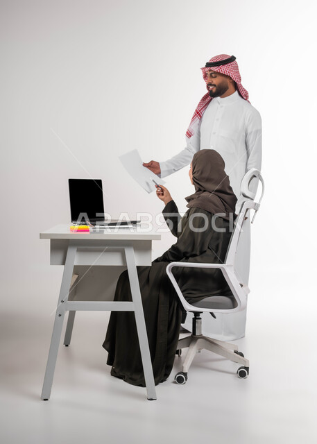 Using modern technologies and methods, teaching employees new methods to achieve the company’s goals, managing and organizing business affairs, a portrait of two Saudi and Gulf Arab colleagues discussing and organizing tasks inside the office, a comfortable and successful work environment, a white background.