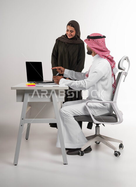 إدارة الأعمال باستخدام التقنيات الحديثة، الاشارة الى الحاسوب المحمول للانتباه للملاحظات وتطبيقها، مفهوم التعاون والعمل الجماعي، متابعة إنجازات مهام الموظفين، بورتريه لموظفين عربيين خليجيين سعوديين يقومان بتطوير الخطط لتحقيق أهداف الشركة، خلفية بيضاء