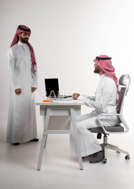 مفهوم العمل الجماعي وروح الفريق الواحد، الرغبة في تعلم اساليب العمل والتطوير المهني، بورتريه لموظفين عربيين خليجيين سعوديين يقومان بإنجاز المهام والأعمال بإستخدام الحاسب المحمول في المكتب، تطوير الخطط وحل المشكلات لتحقيق أهداف الشركة، خلفيه بيضاء