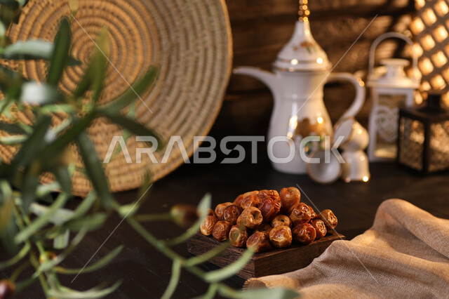 تقديم المشروبات الساخنة، صورة مقربة لدلة قهوة عربية مع فنجانين وطبق من التمر أمام نبتة خضراء، الضيافة السعودية الأصيلة، حسن الضيافه والإستقبال، إفطار رمضاني صحي، الأعياد والمناسبات الدينية، منتجات محلية وطنية . 