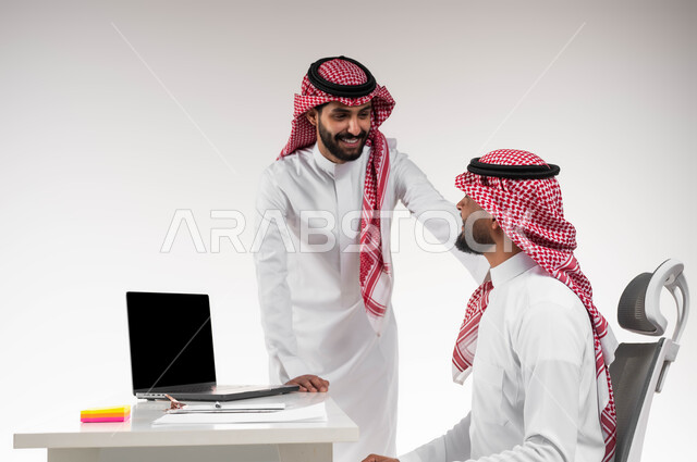 مفهوم الإدارة المتعاونة لتحقيق أهداف الشركة، بورتريه لموظفين عربيين خليجيين سعوديين مبتسمين يرتديان الشماغ والثوب التقليدي يتبادلان الحوارات حول كيفية أداء العمل، الوحدة والتفاعل الجماعي حل المشكلات، إيماءات الحزم والثقة بالنفس، خلفية بيضاء