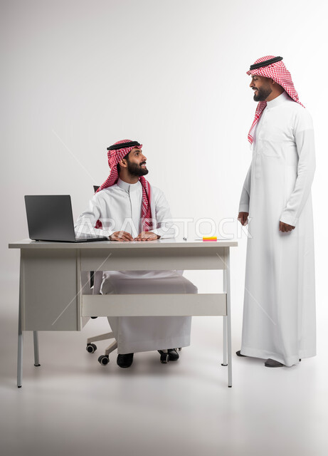 نقاشات وحوارات بين الزملاء، تبادل الخبرات والاتفاقيات الناجحة، مفهوم الإدارة المتعاونة، بورتريه لرجلين عربيين خليجيين سعوديين مبتسمين يرتديان الشماغ والثوب التقليدي يتحادثان بمشاريع العمل، تحقيق مكاسب وأرباح عالية، خلفية بيضاء.