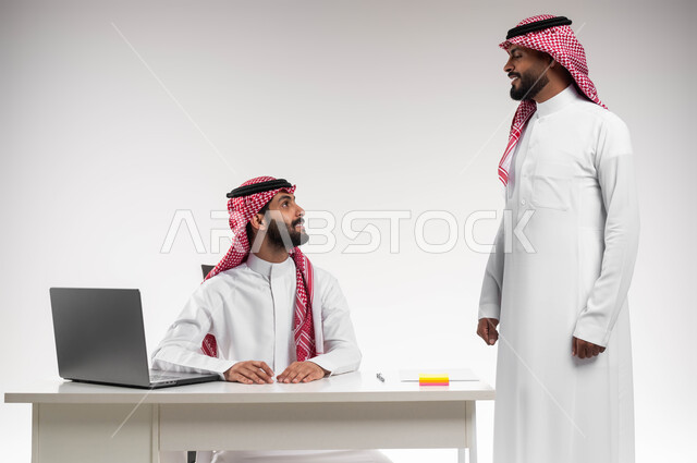 حوارات ونقاشات بين الزملاء، تبادل الخبرات والاتفاقيات الناجحة، مفهوم الإدارة المتعاونة، بورتريه لرجلين عربيين خليجيين سعوديين مبتسمين يرتديان الشماغ والثوب التقليدي يتحادثان بمشاريع العمل، تحقيق مكاسب وأرباح عالية، خلفية بيضاء.