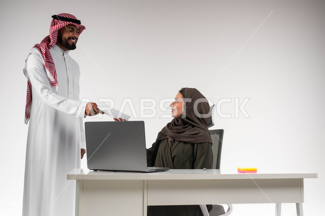 إدارة شؤون الأعمال وتنظيمها، بيئة عمل مريحة و ناجحة، تسليم المشروع بالوقت اللازم، استخدام التقنيات الحديثة ، تحقيق أهداف الشركة بالوقت المطلوب، بورتريه لموظف عربي خليجي يرتدي الزي التقليدي يقوم بتقديم الأوراق لمديرته بإيماءات السرور، خلفية بيضاء