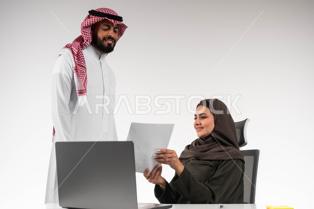 الاشراف على التطور المهني للمهام، تعليم الموظفين الأساليب الجديدة لتحقيق الأهداف المطلوبة، العمل الجماعي وروح الفريق الواحد، بورتريه لزميلين عربيين سعوديين خليجيين يقومان بمناقشة و تنظيم الاعمال داخل مقر الشركة، خلفية بيضاء