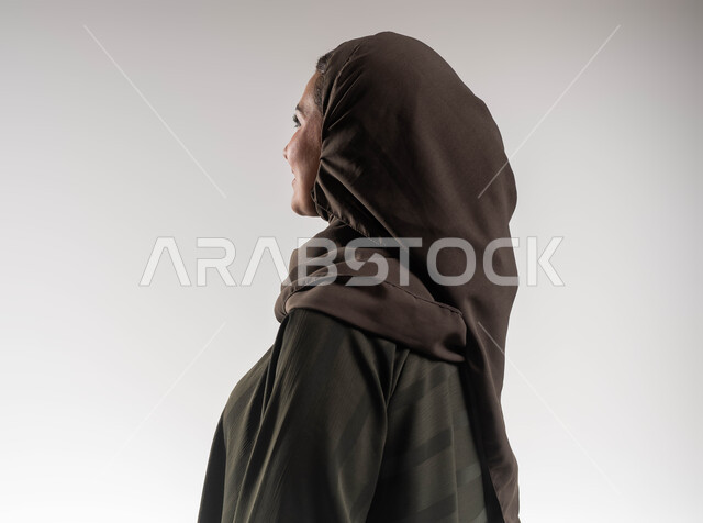التمعن وإيجاد حل لموضوع ما, بورتريه مقرب  من الجانب لإمرأة عربية خليجية سعودية ترتدي العباءة والحجاب تنظر إلى شيء ما, النظرة المستقبلية والتفكير لتحقيق الأهداف, خلفية بيضاء