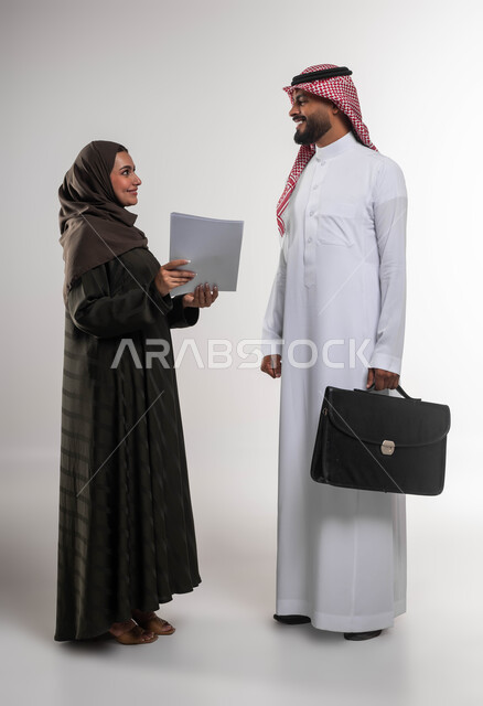 تطوير الخطط وحل المشكلات لتحقيق أهداف الشركة، الرغبة في تعلم اساليب العمل والتطوير المهني، بورتريه لزميلين عربيين خليجيين سعوديين يقومان بمناقشة المهام والأعمال، الانتباه للملاحظات وتطبيقها، العمل الجماعي وروح الفريق الواحد، صورة الجسم بالكامل، خلفيه بيضاء