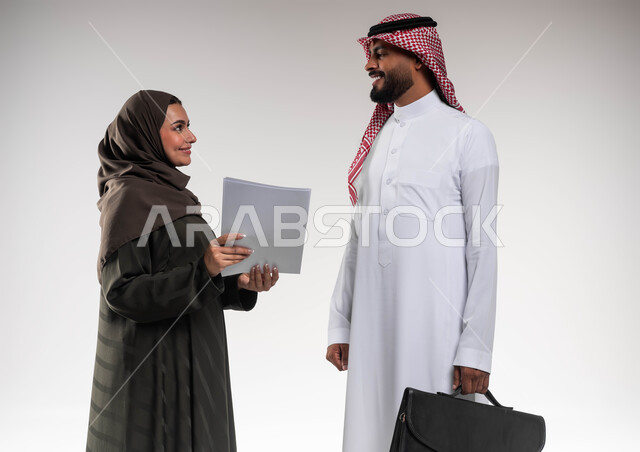 Following up on the accomplishments of employees’ tasks, the desire to learn work methods and professional development, a close-up portrait of two Saudi Gulf Arab colleagues developing plans and solving problems to achieve the company’s goals, paying attention to feedback and applying it, teamwork and one team spirit, a white background.