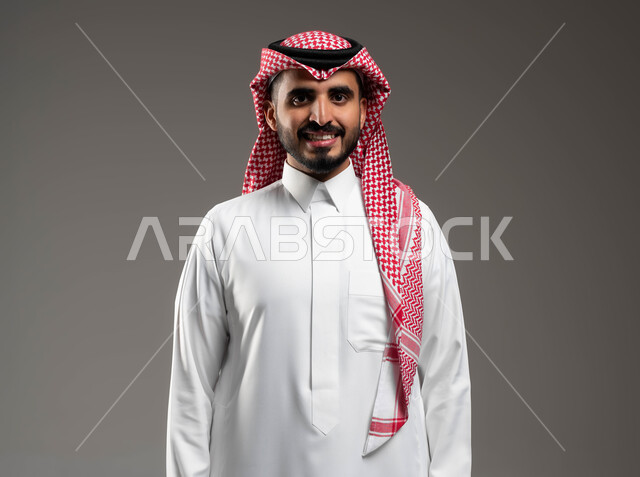 صورة شخصية للوثائق الرسمية، بورتريه مقرب لشاب عربي سعودي خليجي مبتسم يرتدي الشماغ والثوب السعودي التقليدي ينظر إلى الكاميرا بإيماءات السرور والسعادة، الوقوف بإستقامة وثقة بالنفس، خلفية بيضاء