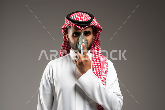 المحافظة على ممر هوائي منتظم باستخدام جهاز التنفس الصناعي، بورتريه مقرب لرجل عربي سعودي خليجي يرتدي الشماغ والثوب التقليدي يقوم باستنشاق أدوية معالجة لانقطاع التنفس عن طريق قناع الاكسجين، مداواة أمراض الربو المزمنة، تقديم الخدمات الصحية المنزلية، خلفية رمادية