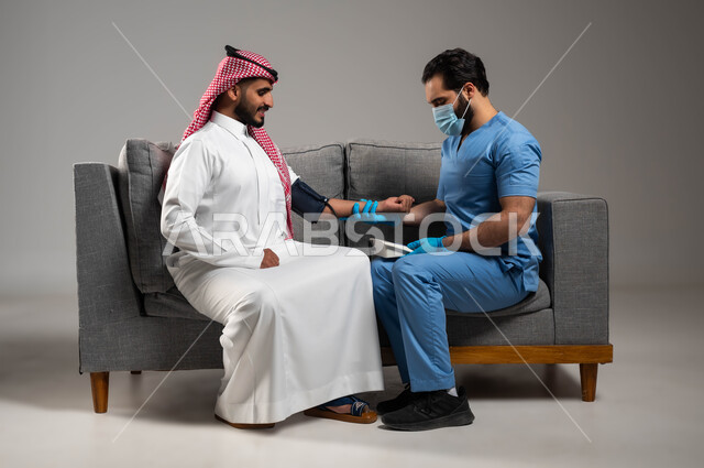 ممرض عربي خليجي سعودي يرتدي القفازات وكمامة الوقاية يقوم بقياس ضغط الدم, العمل في القطاع الصحي, المتابعة الدورية للفحوصات المنزلية, بورتريه لرجل مريض مصاب بوعكة صحية يجلس على الكنبه, مفهوم الصحة والرعاية الطبية, خلفية رمادية