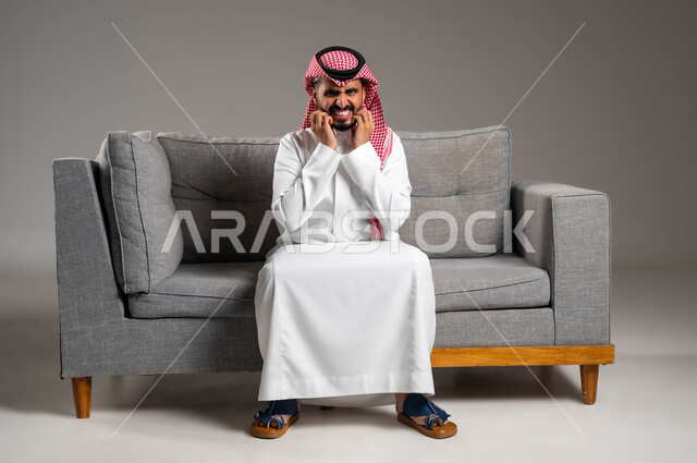 عدم التحمل والشعور بالآلام والأوجاع, بثور منتشرة على بشرة الوجه, المشاكل الصحية والإصابة بالحساسية الجلدية, الأمراض والتهجيات وفرط التحسس, بورتريه لرجل عربي خليجي سعودي يرتدي الثوب والشماغ التقليدي يضع يديه على وجهه بإيماءات الألم, خلفية رمادية