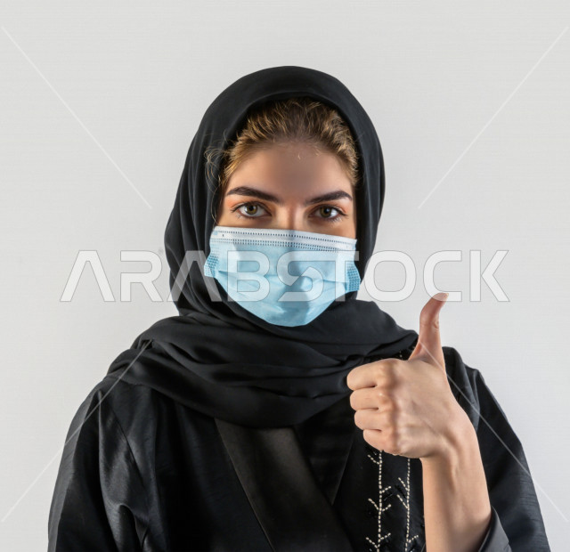 بورتريه لشابة سعودية تقوم بارتداء الكمامة لتجنب تفشي الفايروس ، اتباع اجراءات السلامة بارتداء القفازات ، تجنب انتشار العدوى ، خلفية بيضاء