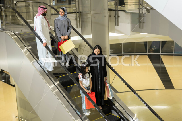 الاستفاده من العروض والتخفيضات الموسمية, سهولة الانتقال من طابق لآخر باستخدام السلالم الكهربائية, مجموعة من المواطنين العرب الخليجيين السعوديين يقومون باستخدام الدرج الكهربائي, متعه التسوق في المولات التجاريه واختيار المستلزمات والهدايا