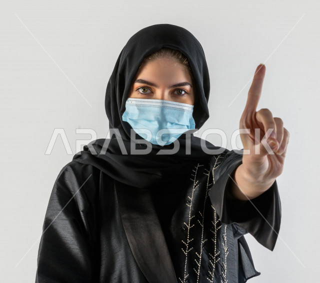 بورتريه لشابة سعودية تقوم بارتداء الكمامة لتجنب تفشي الفايروس ، اتباع اجراءات السلامة بارتداء القفازات ، تجنب انتشار العدوى ، خلفية بيضاء