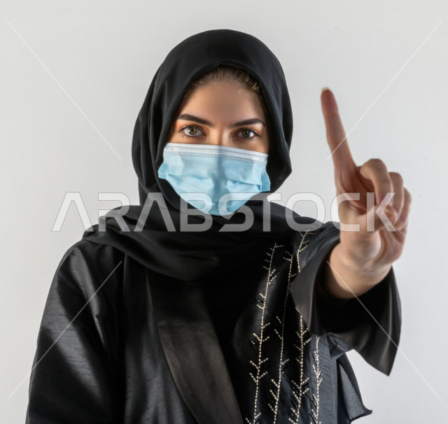 بورتريه لشابة سعودية تقوم بارتداء الكمامة لتجنب تفشي الفايروس ، اتباع اجراءات السلامة بارتداء القفازات ، تجنب انتشار العدوى ، خلفية بيضاء