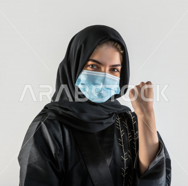 بورتريه لشابة سعودية تقوم بارتداء الكمامة لتجنب تفشي الفايروس ، اتباع اجراءات السلامة بارتداء القفازات ، تجنب انتشار العدوى ، خلفية بيضاء