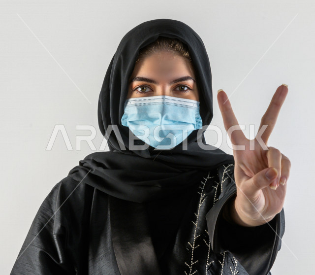 بورتريه لشابة سعودية تقوم بارتداء الكمامة لتجنب تفشي الفايروس ، اتباع اجراءات السلامة بارتداء القفازات ، تجنب انتشار العدوى ، خلفية بيضاء