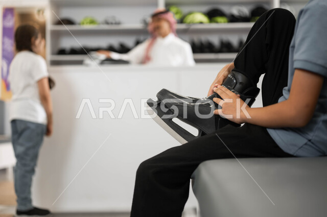 قضاء عطلة صيفيه ممتعه، صورة مقربة لولد عربي خليجي سعودي يقوم بالتجهز لبدء السباقات، اجراء تجارب مثيرة في أحد الأماكن الترفيهيه في السعودية، استعارة الزلاجات من الاستقبال عند مضمار التزلج، تطوير المهارات الرياضية في ساحات التزلج