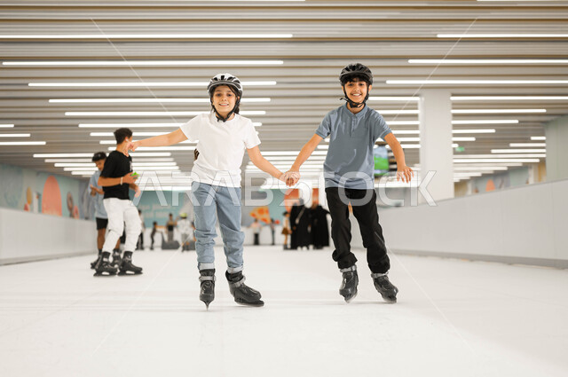 اجراء تجارب مثيرة في مولات السعودية ،النظر الى الكاميرا بإيماءات السرور ،أجواء عائلية مليئة بالحب، ممارسة الألعاب المفضلة في إحدى الأماكن الترفيهيه ،فتاة عربية خليجية سعودية ترتدي خوذة الحماية و تمسك بيد شقيقها وتشاركه في اللعب في ساحات التزلج على الجليد