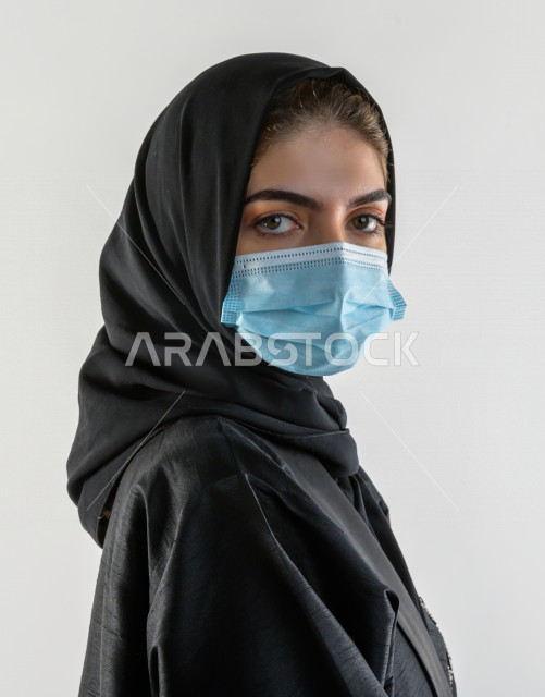 بورتريه لشابة سعودية تقوم بارتداء الكمامة لتجنب تفشي الفايروس ، اتباع اجراءات السلامة بارتداء القفازات ، تجنب انتشار العدوى ، خلفية بيضاء