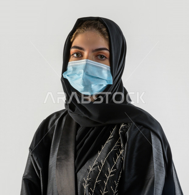 بورتريه لشابة سعودية تقوم بارتداء الكمامة لتجنب تفشي الفايروس ، اتباع اجراءات السلامة بارتداء القفازات ، تجنب انتشار العدوى ، خلفية بيضاء