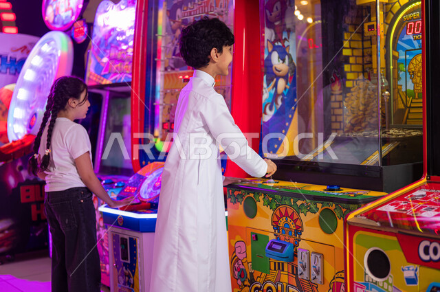 فعاليات ومنافسات في اللعب بين الأخوة، قسم التحديات والمغامرات، المراكز الترفيهية في المملكة العربية السعودية، الاستمتاع في قضاء عطلة صيفية ممتعة، ولد عربي سعودي خليجي يلعب مع أخته في ألعاب الأركيد الالكترونية، الشعور بالمتعة والفرح .