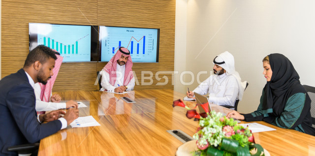 اجتماع اداري مع مجموعة من الأشخاص السعوديين الخليجيين في غرفة الاجتماعات  ، اجتماع رجال اعمال و سيده اعمال سويا داخل الشركة ،  شركة سعودية ، عمل خليجي ،  فريق العمل 