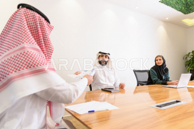 اجتماع اداري مع مجموعة من الأشخاص السعوديين الخليجيين في غرفة الاجتماعات  ، اجتماع رجال اعمال و سيده اعمال سويا داخل الشركة ،  شركة سعودية ، عمل خليجي ،  فريق العمل 