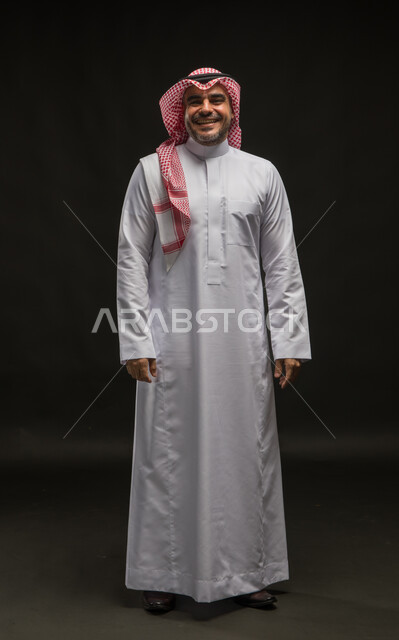 The concept of caring about external appearance, masculinity and elegance, a personal photo for official documents, a portrait of a smiling Saudi Arabian Gulf man wearing a shemagh and traditional dress, standing straight and looking at the camera with gestures of joy and happiness, full-length body photo, black background