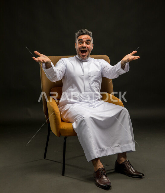 تعابير الدهشة والسرور برؤية شخص ما، فوز المنتخب المفضل في المباراة، الترحيب والاستقبال بحرارة وبشاشة، بورتريه لرجل عربي خليجي سعودي مبتسم يرتدي الثوب التقليدي يرفع كفيه للأعلى وينظر إلى الكاميرا بإيماءات السعادة والاستغراب، خلفية سوداء.