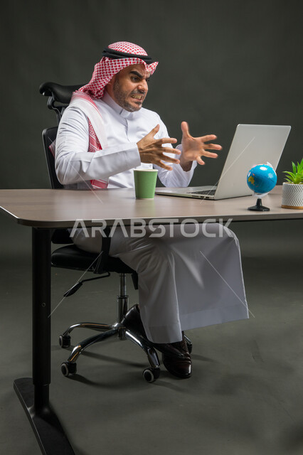 Movements and expressions indicating irritation and extreme tension, gestures of annoyance and nervous pressure, feeling angry and failing to achieve the company’s goals, portrait of a Saudi Arabian Gulf businessman wearing a shemagh and traditional thobe, sitting in his office using a laptop, black background