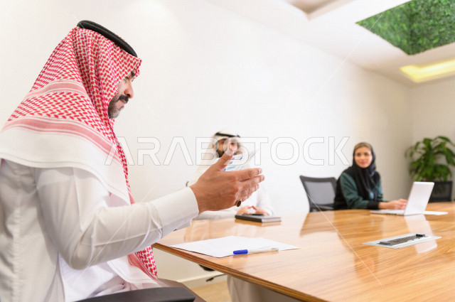 اجتماع اداري مع مجموعة من الأشخاص السعوديين الخليجيين في غرفة الاجتماعات  ، اجتماع رجال اعمال و سيده اعمال سويا داخل الشركة ،  شركة سعودية ، عمل خليجي ،  فريق العمل 