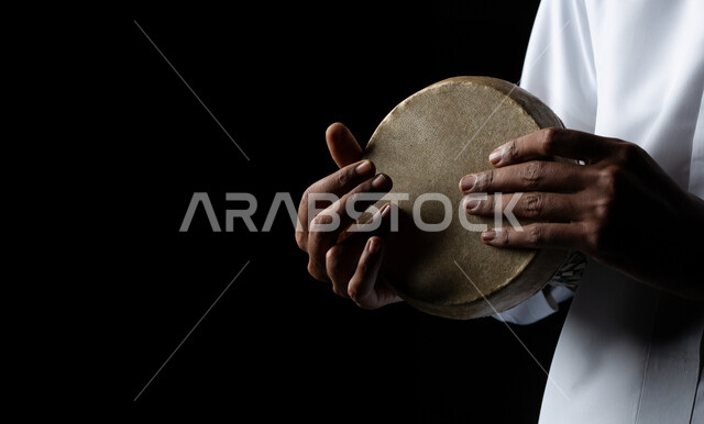 مواهب فنية موسيقية، قرع الطبول باستخدام الآلات الايقاعية، بورتريه مقرب لرجل عربي سعودي خليجي فنان يقوم بممارسة هواية الطبل على الطبلة السعودية، تقديم البرامج والفنون الغنائية والفن المسرحي، خلفية سوداء