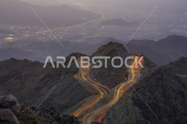 الطبيعة والبيئة الجبلية والقمم والمرتفعات في المملكة العربية السعودية، صورة جوية من الأعلى لحركة مرور وسير السيارات على جبال الهدا في مدينة الطائف، طريق اسفلتي ملتوي وعر وسط الجبال الصخرية في منطقة عقبة الهدا في وقت اللليل