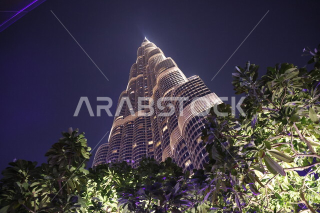 صورة من الأسفل لبرج خليفة المضاء في وقت الليل في إمارة دبي، معالم سياحية مشهورة في الإمارات العربية المتحدة، الفن الهندسي المعماري للأبراج وناطحات السحاب، العمل على تنمية وتطوير الأبراج والمباني، الاهتمام بالتشجير في المدن السياحية والاماكن العامة