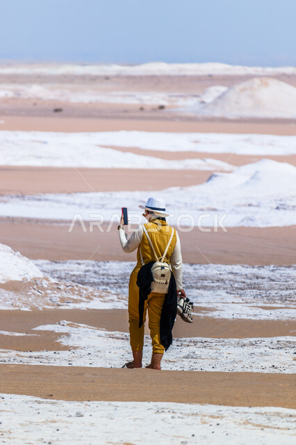 التسلية وقضاء وقت ممتع, الاستمتاع بالأجواء الشتوية الثلجية, معالم سياحية طبيعية مشهورة, رحلات السفاري الترفيهية والاستكشافية في المملكة العربية السعودية, صورة من الخلف لفتاة عربية خليجية سعودية تردي الزي الكاجوال تقوم بالتقاط صور تذكارية عبر الجوال