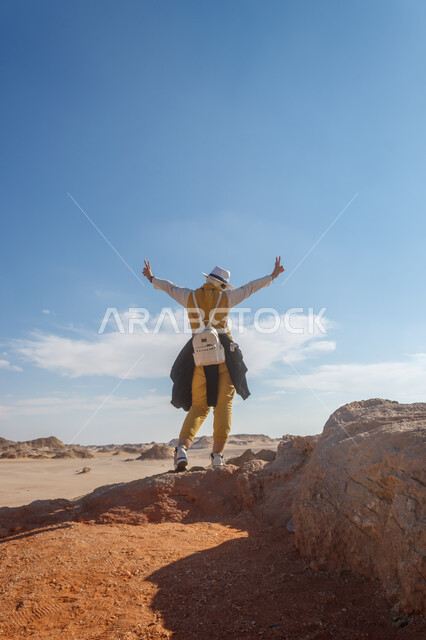 Recreational and exploratory safari trips in the Kingdom of Saudi Arabia, a picture from the back of a Saudi Gulf Arab girl wearing a casual outfit enjoying in one of the mountainous areas, entertainment, entertainment and spending a good time, famous natural tourist attractions