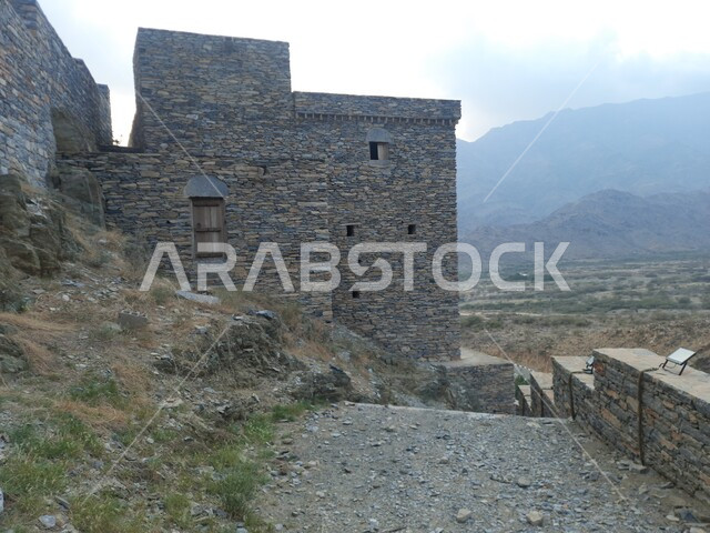 The traditional architectural design of the village houses, famous mountainous tourist landmarks, the historic village of Dhi Al-Ain in the Al-Baha region, the building constructed of stones and trunks of Sidr trees, the unique urban art of volcanic stones, green plants and fertile soil