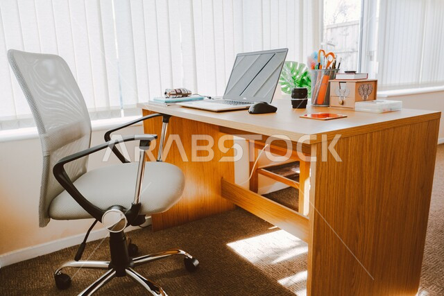 بيئة عمل مكتبة مريحة، جهاز الحاسوب على طاولة المكتب الخشبية, مفهوم التعليم عن بعد عبر التكنولوجيا, استخدام الأجهزة الذكية والمتطورة للدراسة وحضور المحاضرات اونلاين, شركات ومكاتب أعمال في المملكة العربية السعودية.