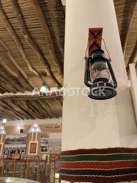 الفوانيس المعدنية المعلقة على الأسقف الخشبية داخل متحف العقيلات في مدينة بريدة في منطقة القصيم, أداوت إنارة بدائية تراثية تقليدية, صورة مقربة لفانوس شعبي عربي سعودي تقليدي, الفن الهندسي والتصميم الداخلي على الطراز القديم