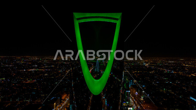 الفخر بالانتماء للهوية الوطنية, صورة مقربة لمبنى برج المملكة المضاء باللون الأخضر في مدينة الرياض بالسعودية في وقت الليل، احتفالات اليوم الوطني السعودي في 23 سبتمبر، فعاليات يوم التأسيس السعودي 22 فبراير, الفن الهندسي المعماري للمباني والمنشآت في العاصمة