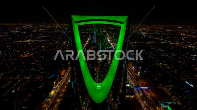 الفخر بالانتماء للهوية الوطنية, صورة مقربة لمبنى برج المملكة المضاء باللون الأخضر في مدينة الرياض بالسعودية في وقت الليل، احتفالات اليوم الوطني السعودي في 23 سبتمبر، فعاليات يوم التأسيس السعودي 22 فبراير, الفن الهندسي المعماري للمباني والمنشآت في العاصمة