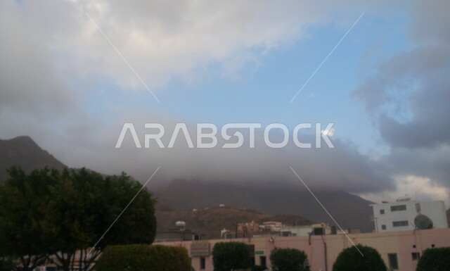 منظر السماء الملبدة بالغيوم، المباني والبيوت الأثرية القديمة، القمم والمرتفعات الجبلية، المناطق والمعالم التاريخية السياحية المشهورة في المملكة العربية السعودية، قرية رجال ألمع التراثية في منطقة عسير، الأشجار والنباتات الخضراء في القرى