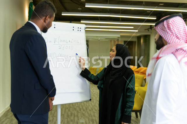 اجتماع اداري مع مجموعة من الأشخاص السعوديين مكون من سيدة اعمال  و رجال اعمال  داخل الشركة ، تقديم الأفكار للزملاء في المكتب عل لوحة بيضاء  ،  شركة سعودية ، عمل خليجي ،  فريق العمل ، دورات تدريبية ، دورات و متدربين  ، بيئة العمل