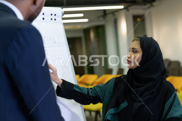 اجتماع اداري مع مجموعة من الأشخاص السعوديين مكون من سيدة اعمال  و رجال اعمال  داخل الشركة ، تقديم الأفكار للزملاء في المكتب عل لوحة بيضاء  ،  شركة سعودية ، عمل خليجي ،  فريق العمل ، دورات تدريبية ، دورات و متدربين  ، بيئة العمل